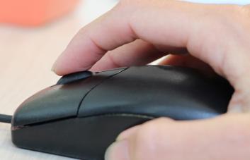 Main posée sur une souris informatique