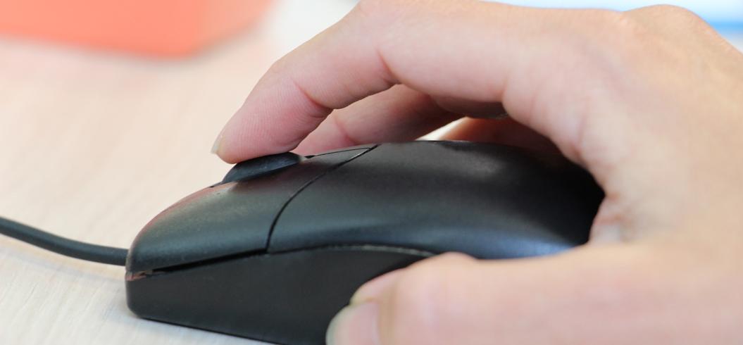 Main posée sur une souris informatique